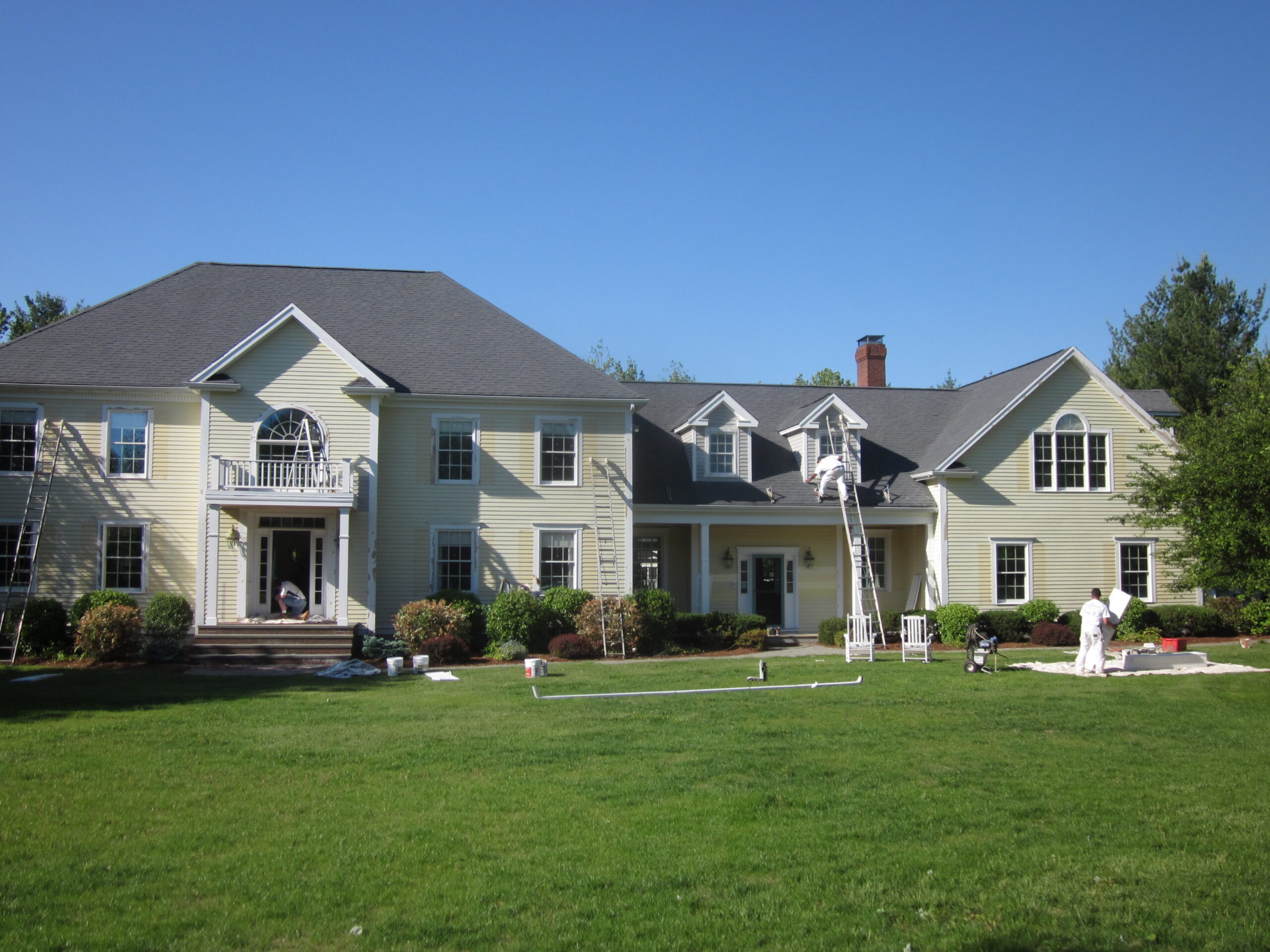 Large multi-unit residential building with light-colored siding, balconies, and a wide green lawn in front.