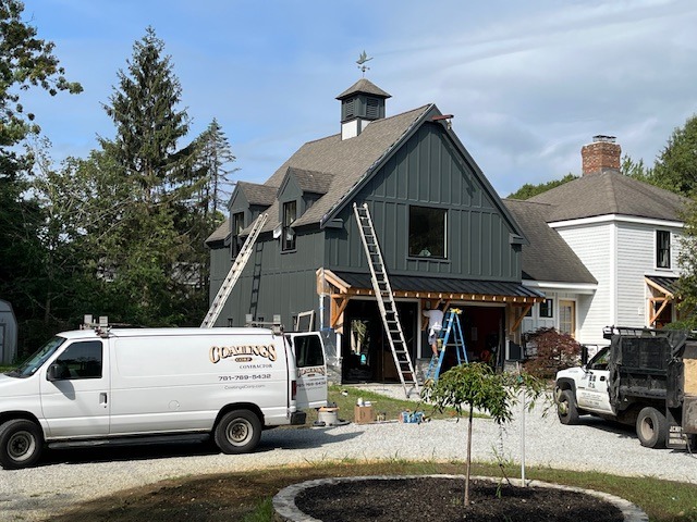 House renovation scene with construction equipment and a service truck parked in the driveway.