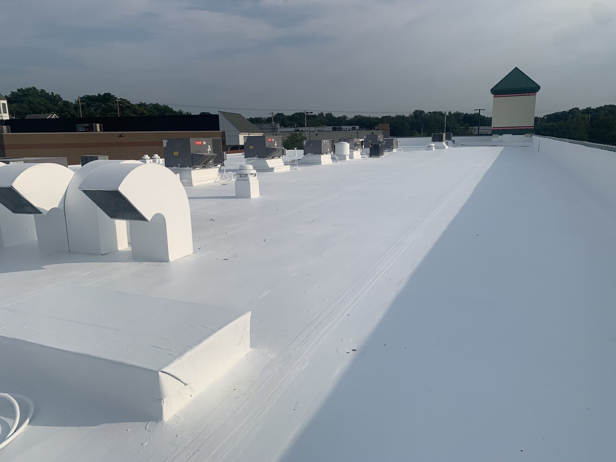 White flat rooftop with multiple vents and skylight structures extending across the surface.